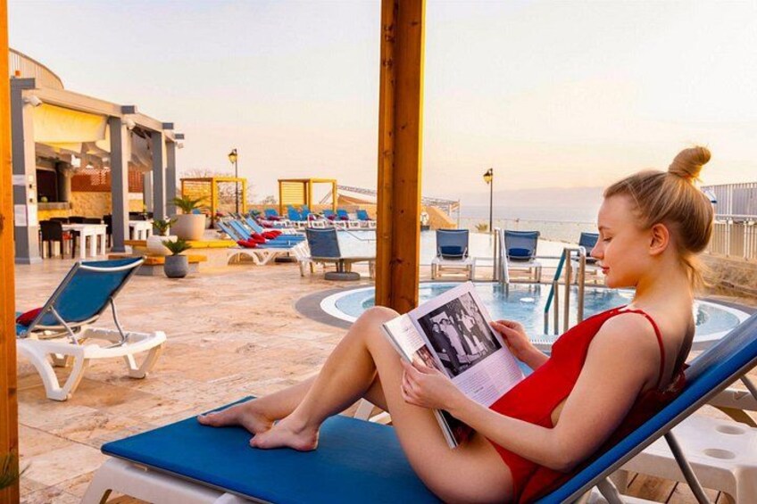 A person sitting on a lounge chair by a pool, reading a book. 4
