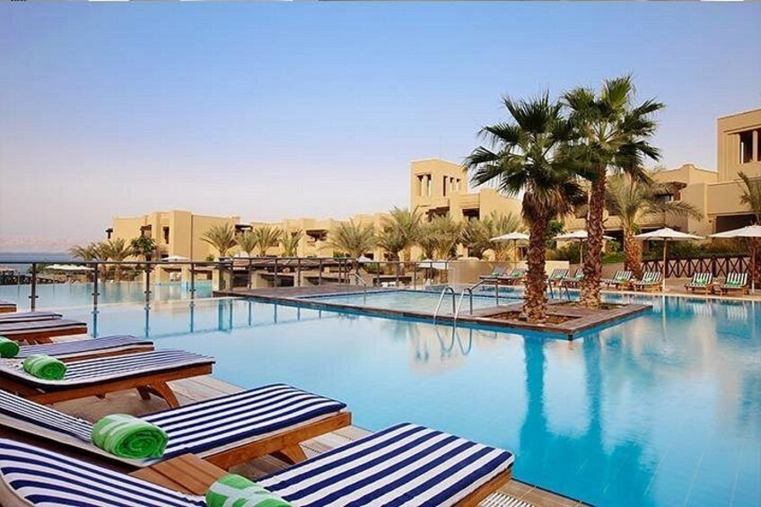 A swimming pool with lounge chairs, palm trees, and resort buildings. 5