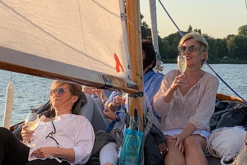 People on a sailboat with a lake and trees in the background. 3