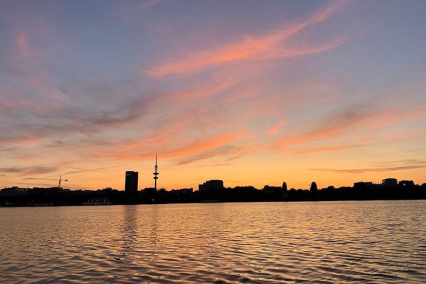 A sunset over a body of water with a city skyline in the background. 2