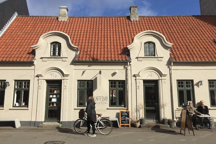 A building with a red-tiled roof and a sign that reads 'KAFFEBAR'. 4