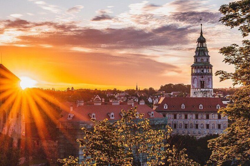 A historic building with a tower, surrounded by trees and a sunset. 5