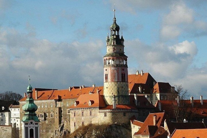 A historic building with a prominent tower, red-roofed structures, and a clear sky. 4