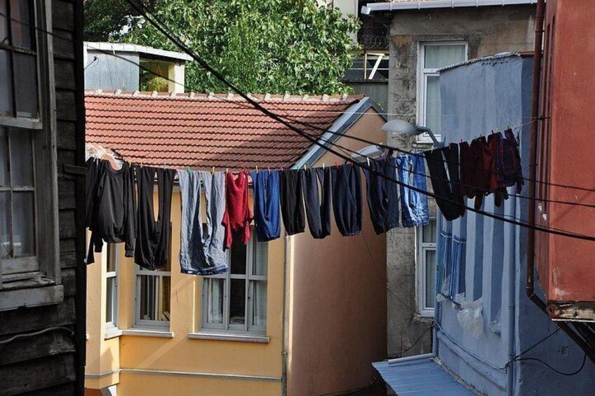 Une corde à linge sur laquelle sont suspendus différents vêtements, un bâtiment avec un toit recouvert de tuiles rouges et un arbre en arrière-plan. 3