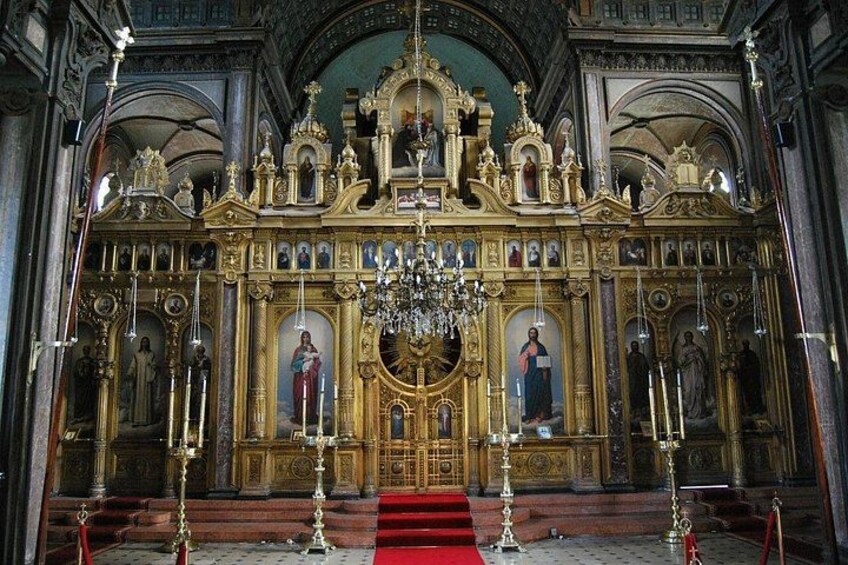 An ornate religious interior with golden altars, statues, and a chandelier. 2