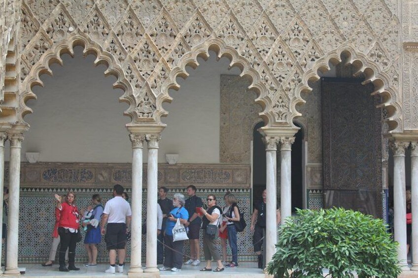 A group of people standing under a decorative archway with intricate patterns. 3