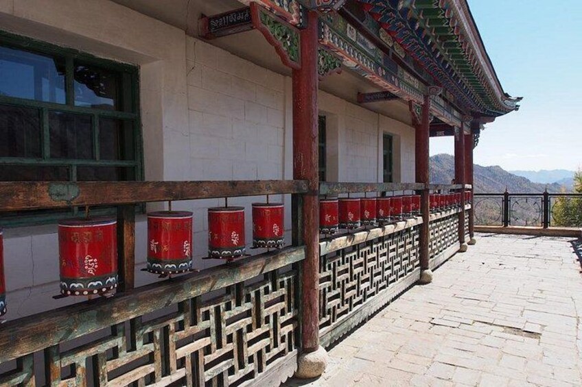 A traditional building with red lanterns, a tiled walkway, and a mountainous backdrop. 2