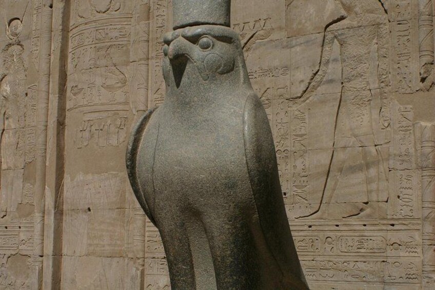 A stone sculpture of an owl with hieroglyphs in the background. 3