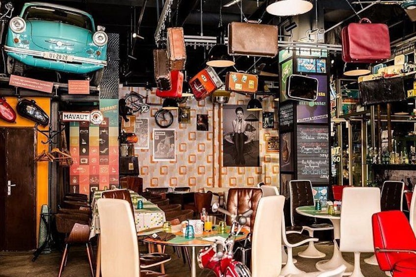 A vintage-themed restaurant interior with retro furniture, hanging luggage, and classic decor. 2