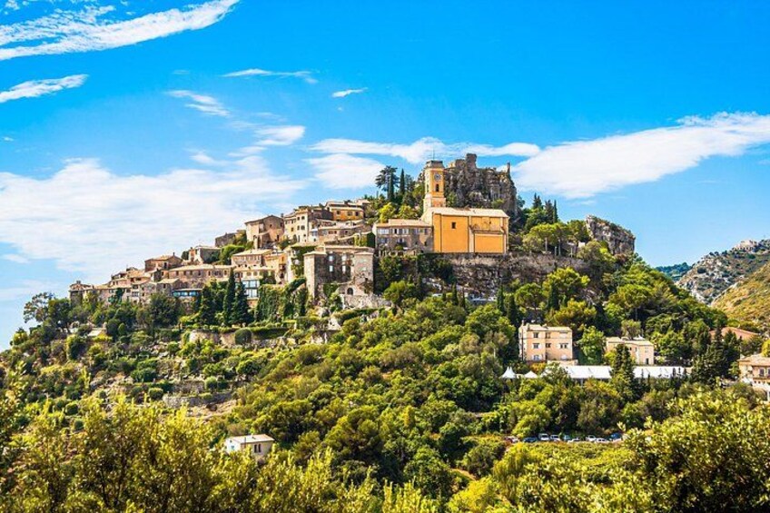 A hillside village with historic buildings, a prominent church, and lush greenery. 1