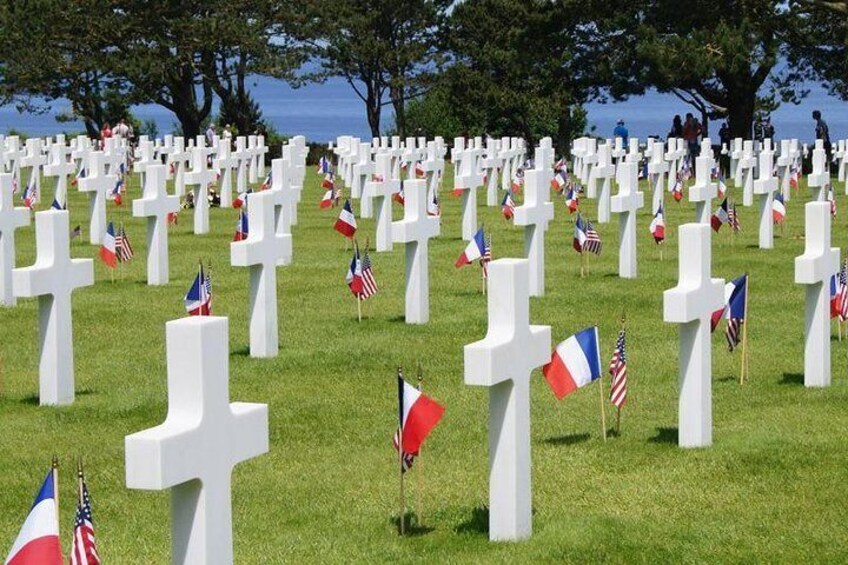 Ein Friedhof mit zahlreichen weißen Kreuzen und französischen sowie US-amerikanischen Flaggen. 5