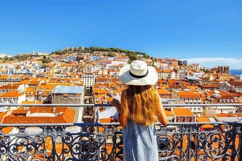 Una persona observa un paisaje urbano costero con edificios de tejados rojos y un cielo azul despejado. 2