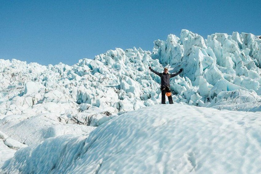 Una persona está de pie en una ladera cubierta de nieve con una gran formación de hielo al fondo. 3