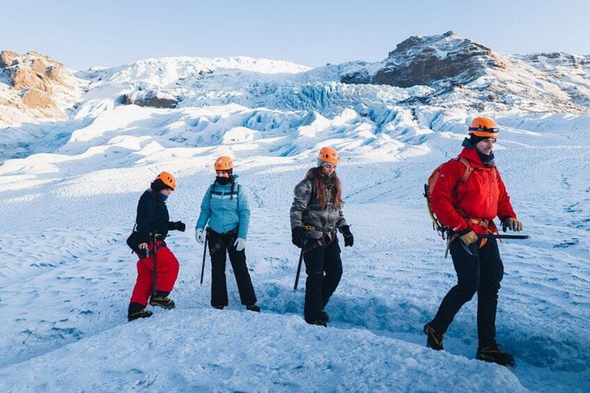 Een groep mensen wandelt over een besneeuwde berg met een gletsjer op de achtergrond. 1