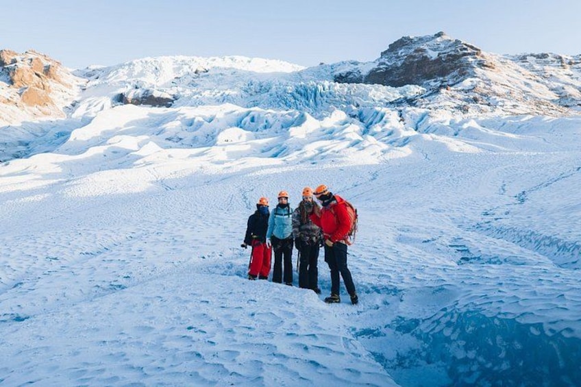 Un grupo de personas en una montaña nevada, con un glaciar al fondo. 4
