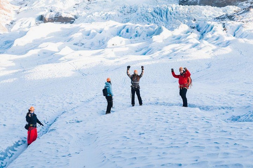 A group of people on a snowy mountain with a glacier in the background. 3