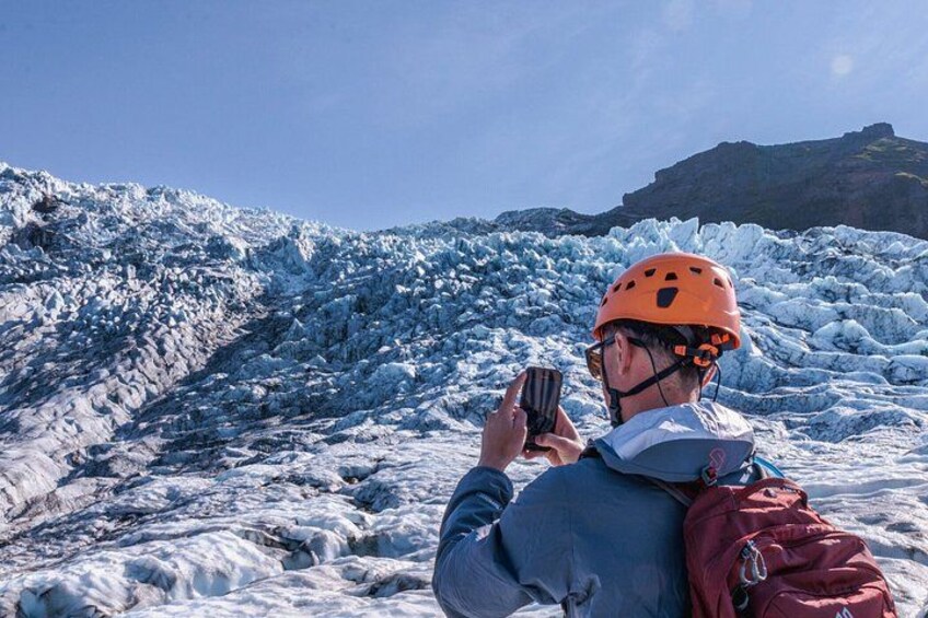 A person taking a photo of a glacier with a smartphone. 4