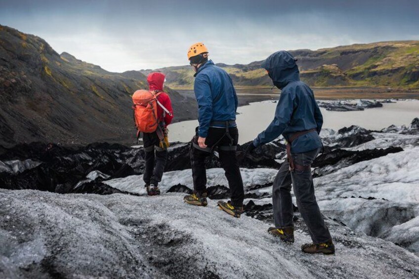 Three hikers on a glacier with a lake and mountains in the background. 5