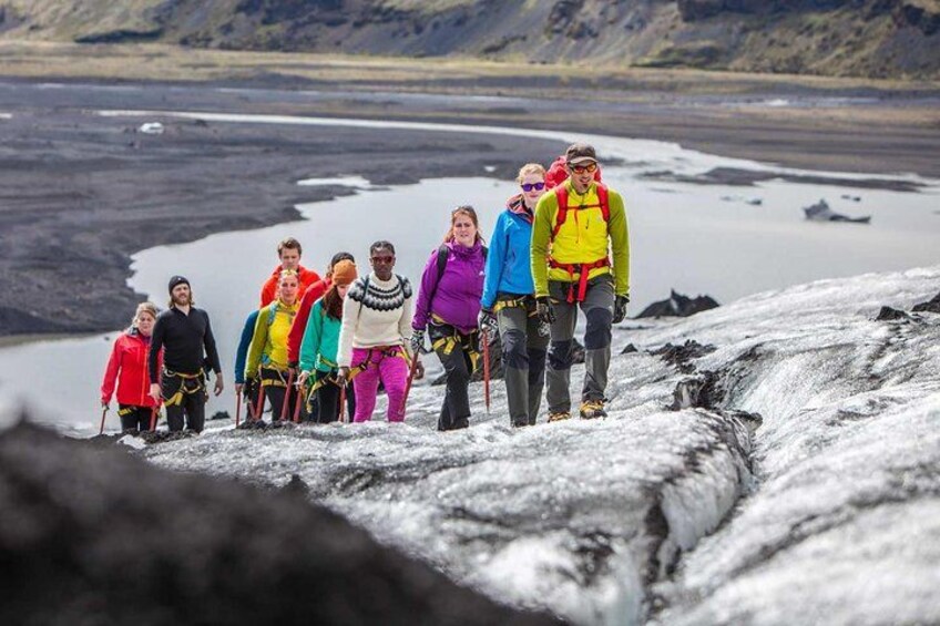 Eine Gruppe von Wanderern auf einem Gletscher, im Hintergrund ein Gewässer. 3