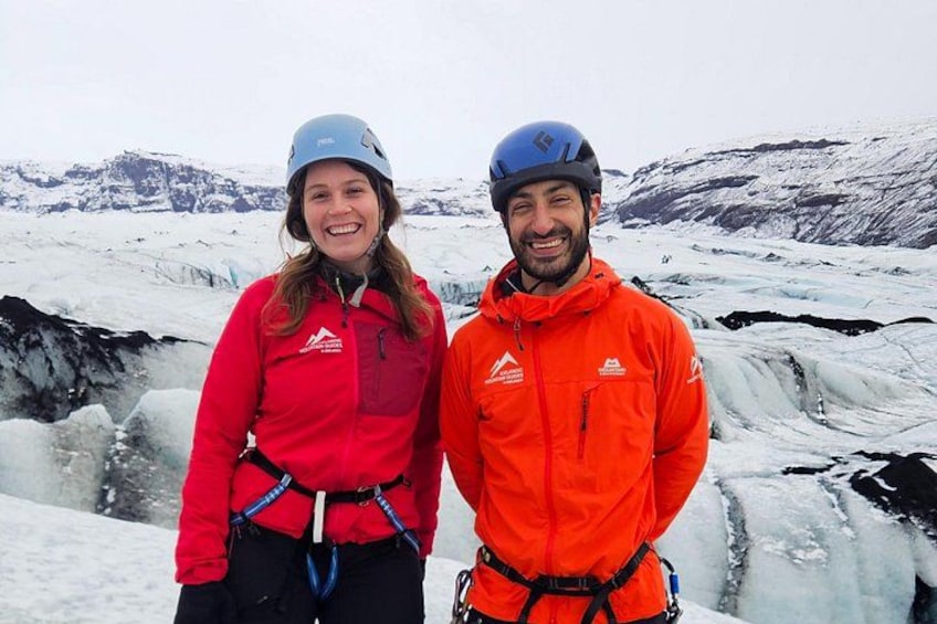 Zwei Personen mit Helmen und roten Jacken stehen vor einem Gletscher. 4