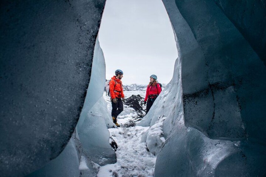 Two people in red jackets navigating a narrow ice passage. 5