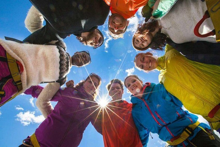 A group of people standing in a circle with the sun shining through their heads. 4