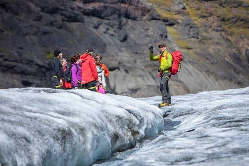 A group of people on a glacier with a guide leading them. 3