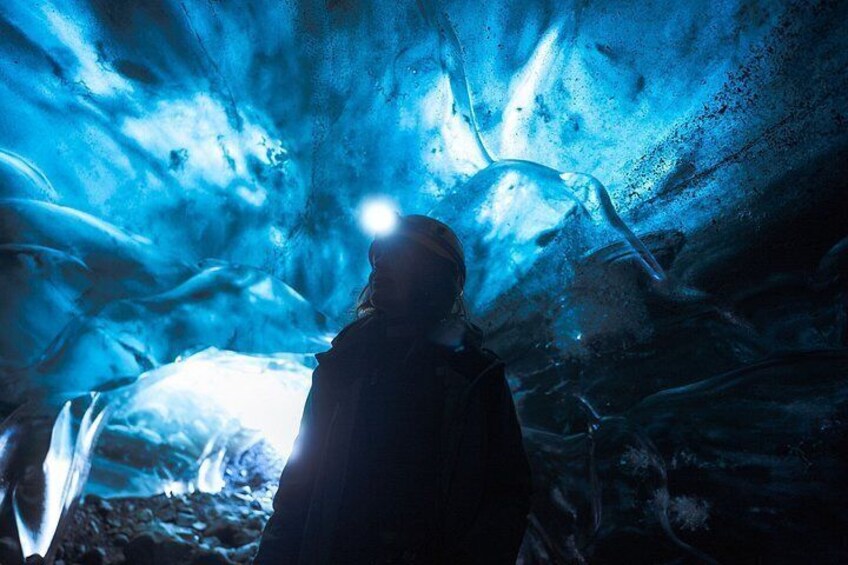 Una persona dentro de una cueva de hielo con formaciones de hielo azulado. 5