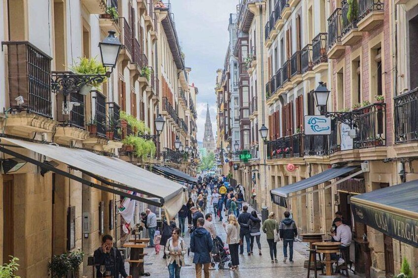 Een levendige straat met gebouwen, mensen die lopen en terrasjes. 5