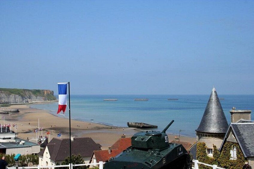 A beach with a flag, a tank, and a building with a pointed roof. 4