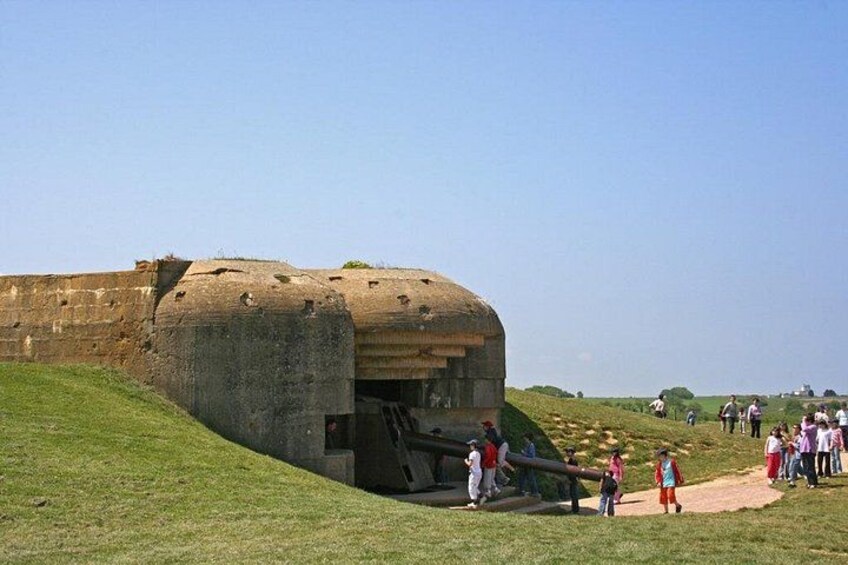 A large, ancient stone structure with a dome, surrounded by a grassy area with people walking around. 5