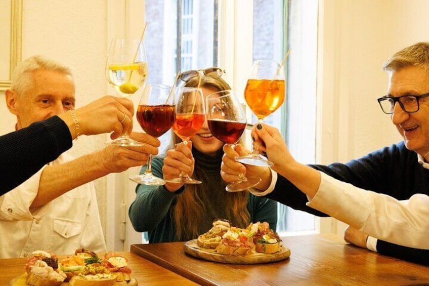 Three people toasting with wine glasses at a table with food. 4