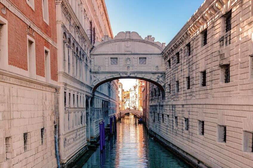 A canal with buildings on either side, a bridge, and a clear sky. 3
