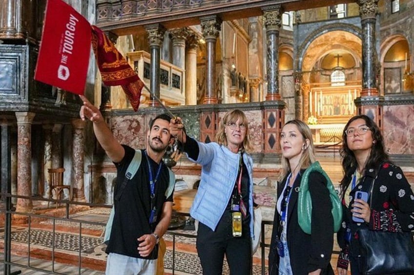 A group of people inside a historical building with ornate architecture, including columns and arches. 3