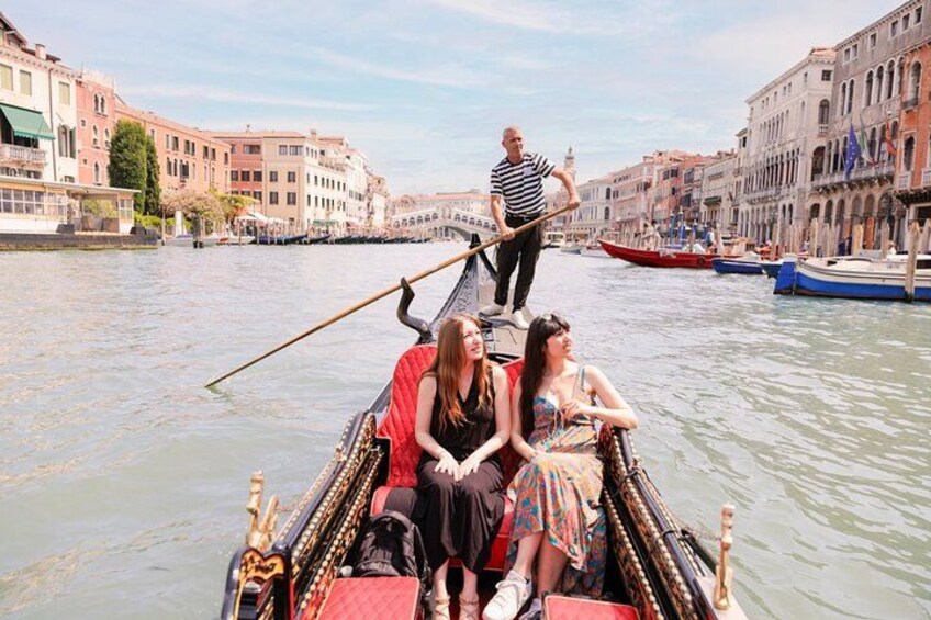 A gondola with passengers, a gondolier, and a canal with buildings in the background. 2