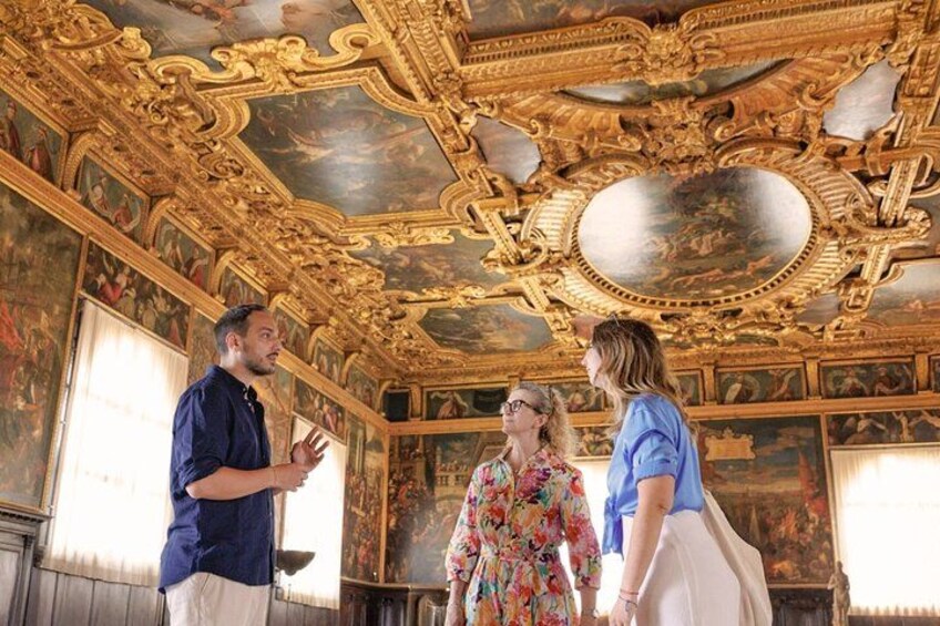 A room with ornate golden ceilings and classical paintings. 4
