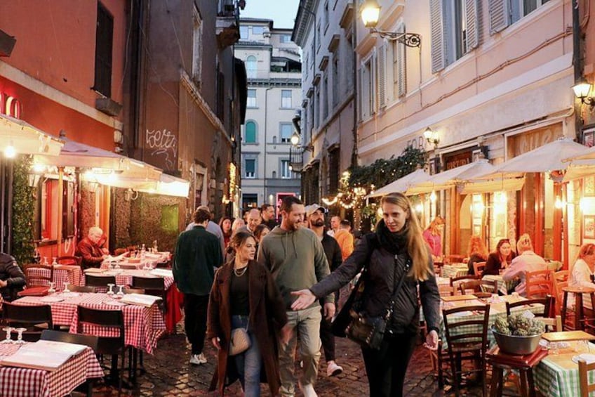 Une rue animée, avec des tables installées à l’extérieur des restaurants, des passants et des immeubles abritant des boutiques. 1