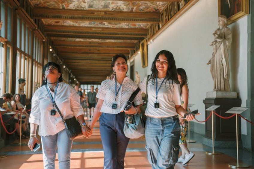 A group of people walking in a museum with classical architecture and statues. 5