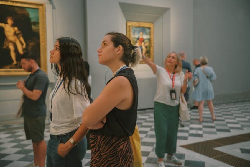 An art gallery with visitors observing paintings. 3