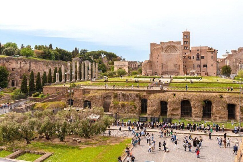 Ancient ruins with columns, a large building, and a crowd of people. 2