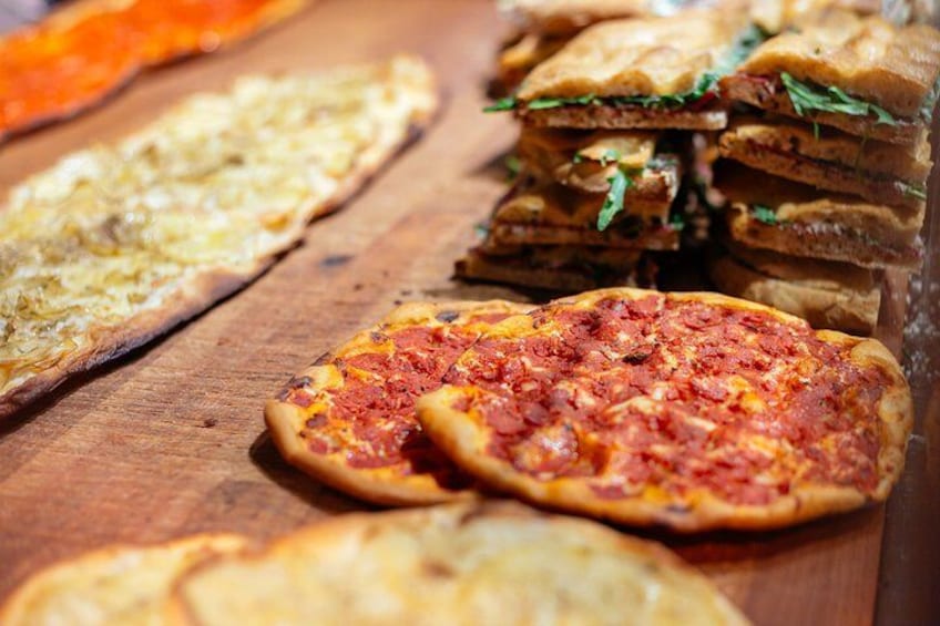 Various types of flatbreads and pizzas on a wooden surface. 3