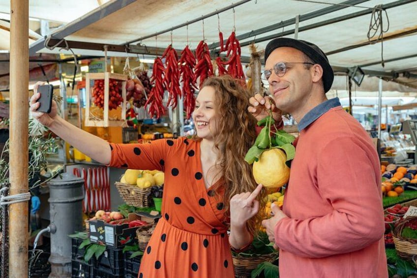 A person taking a selfie with another person holding a fruit. 5