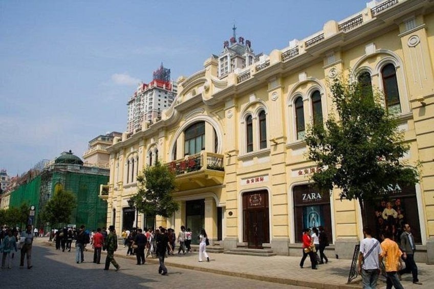 A busy urban street with pedestrians, a Zara store, and classical architecture. 4