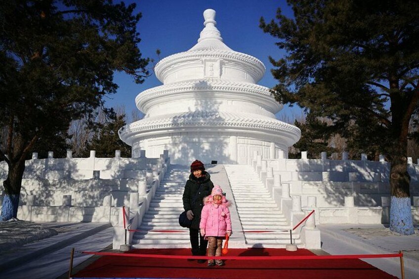 A white pagoda with a red carpet leading up to it, surrounded by snow-covered steps and trees. 5