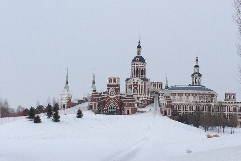A snow-covered landscape with a large, ornate building featuring multiple towers and domes. 5
