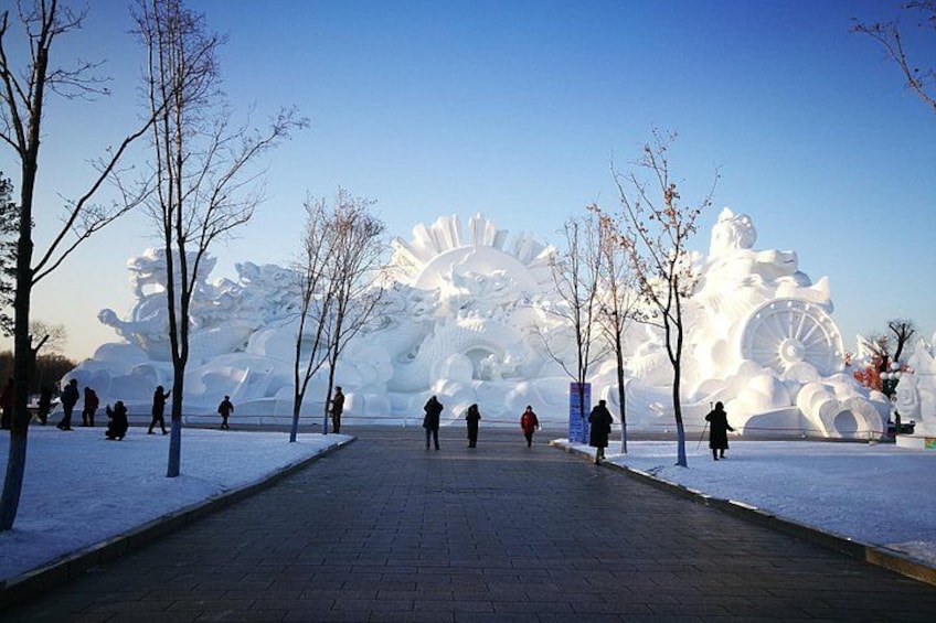 A snow-covered pathway with sculptures and leafless trees. 5