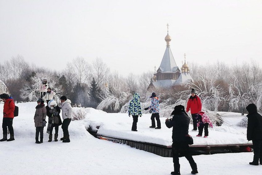 A group of people standing on a snow-covered slope with a church in the background. 2