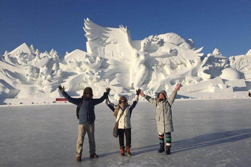 Three people standing in front of a large snow sculpture. 1