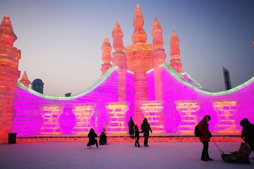 An illuminated ice sculpture with a castle-like structure and arches. 5