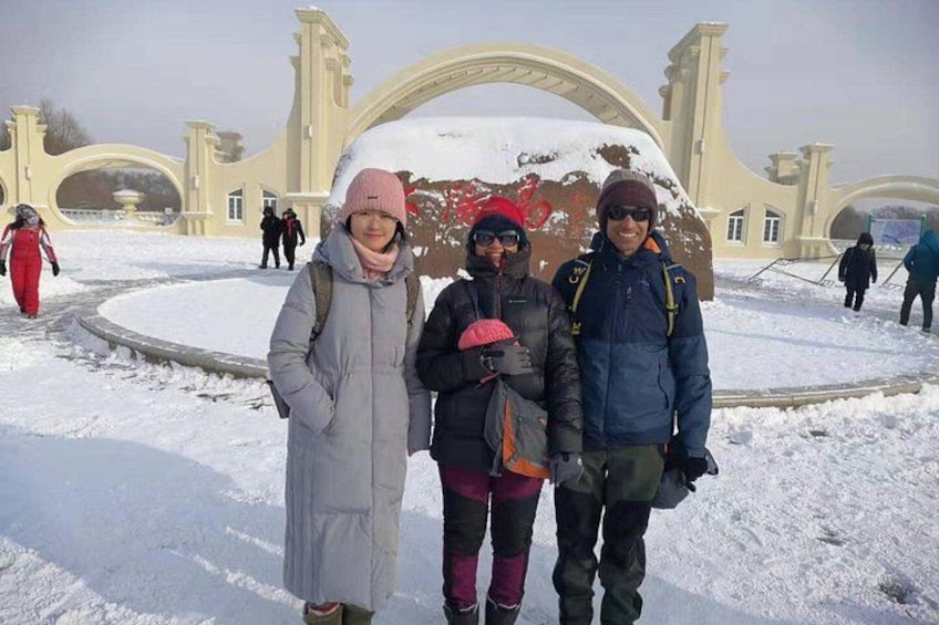 A snowy landscape with a large arch structure and people walking around. 2